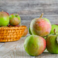 Chilly apples in a wicker basket on a wooden background. side view.