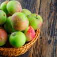 Juicy apples in a wicker basket on a wooden background. close-up.