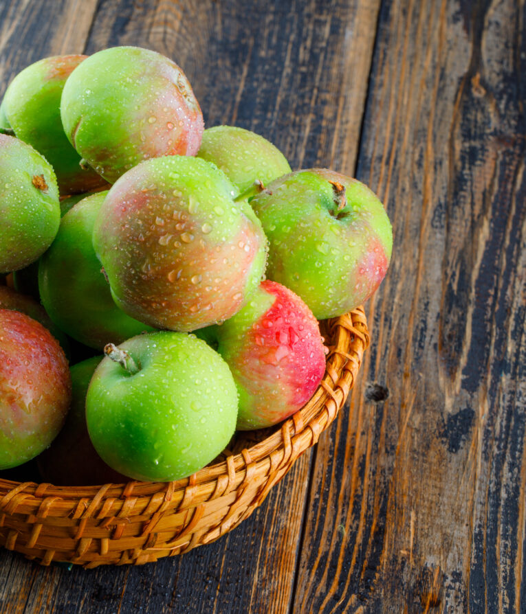 Juicy apples in a wicker basket on a wooden background. close-up.